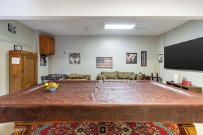 Ein Konferenzraum mit einem großen Tisch, einer Couch und verschiedenen Wanddekorationen, darunter Tierporträts und eine Flagge.