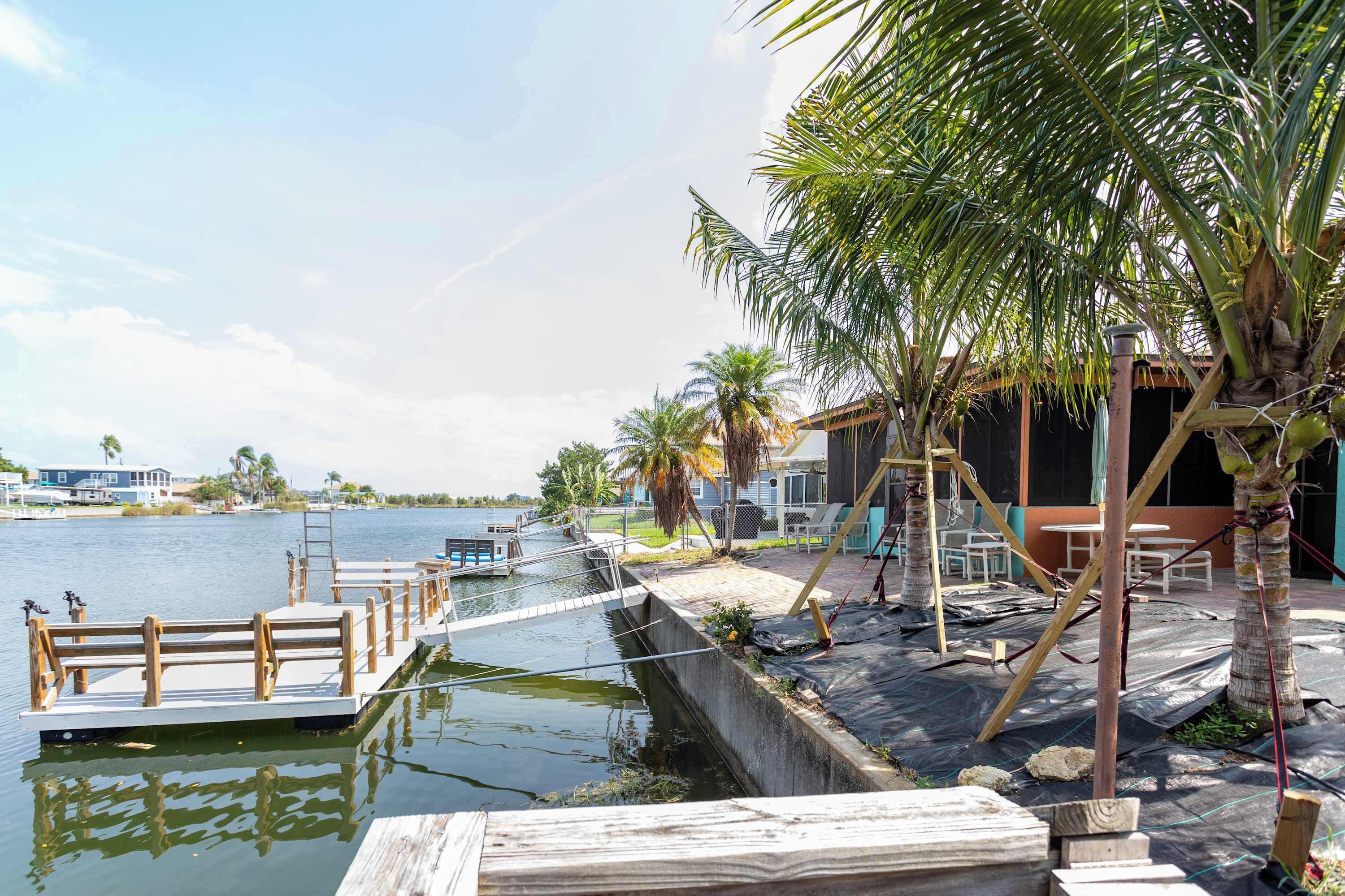 A waterfront property with a dock, palm trees, and a building with outdoor seating.