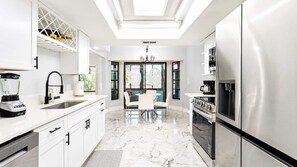 A modern kitchen with a central island, stainless steel appliances, and a dining area with a chandelier. - Hernando Beach 3BR - Water Views, Fireplace (Hernando Beach)