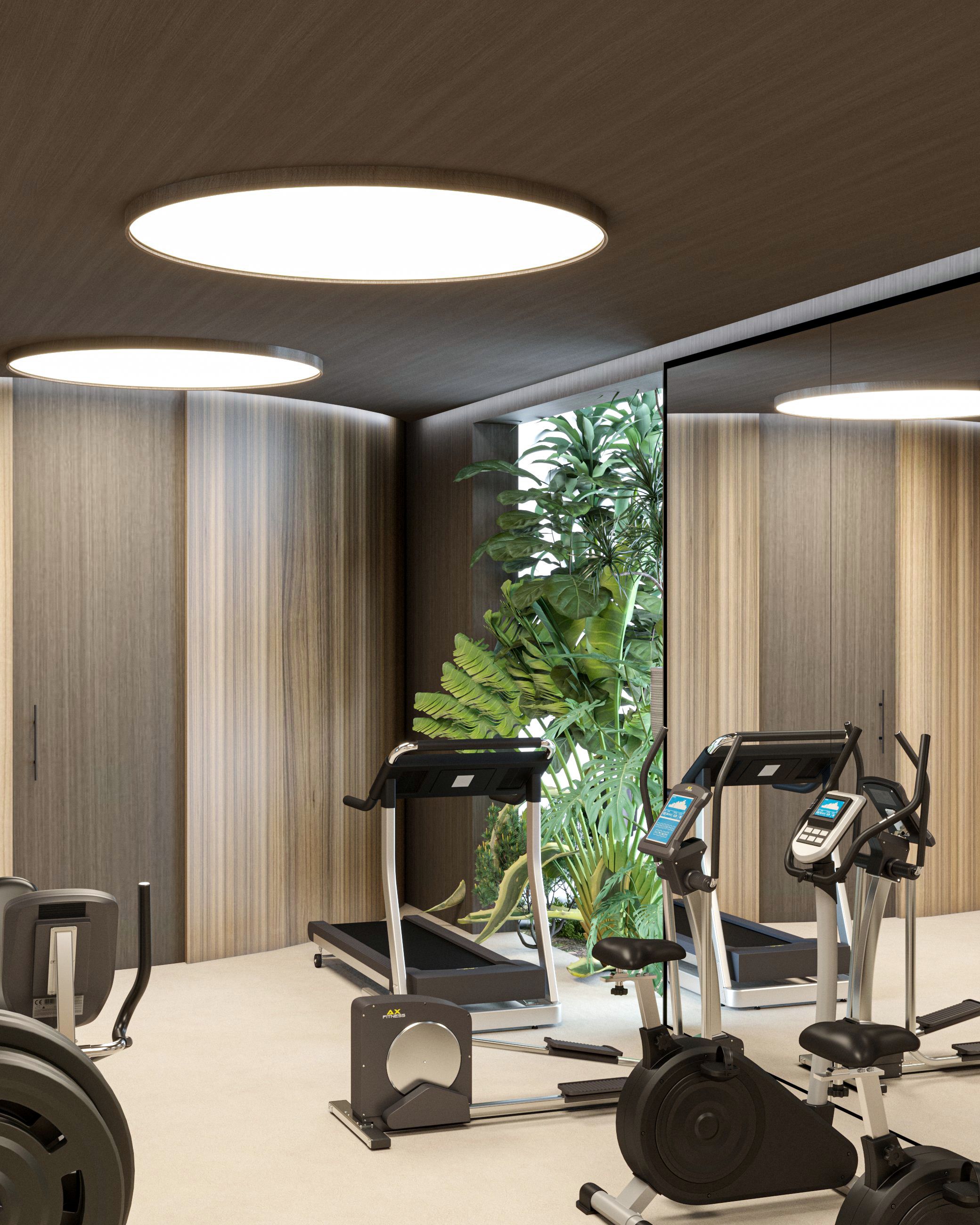 A gym with exercise equipment, including treadmills and a stationary bike, with a large mirror and a plant in the background.