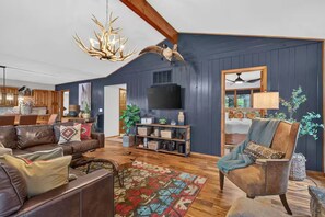 A spacious living room with a large wooden ceiling, a fireplace, and a television mounted on the wall. - Lakeside Walk-In from House - Luxury Lake Cabin - Big Views - Pool Table (Shell Knob)
