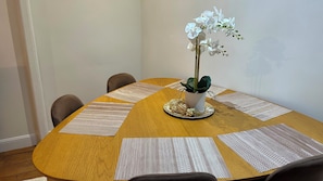 A round wooden table with a potted orchid, a decorative plate, and a placemat with text. - Place du Trocadéro (5-minute walk) - Elegant 3-room apartment, 50 m² (max. 6 people) (Paris)