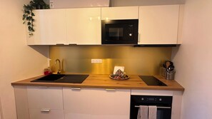 A modern kitchen with white cabinets, a black microwave, a sink, and a dish rack. - Place du Trocadéro (5-minute walk) - Elegant 3-room apartment, 50 m² (max. 6 people) (Paris)