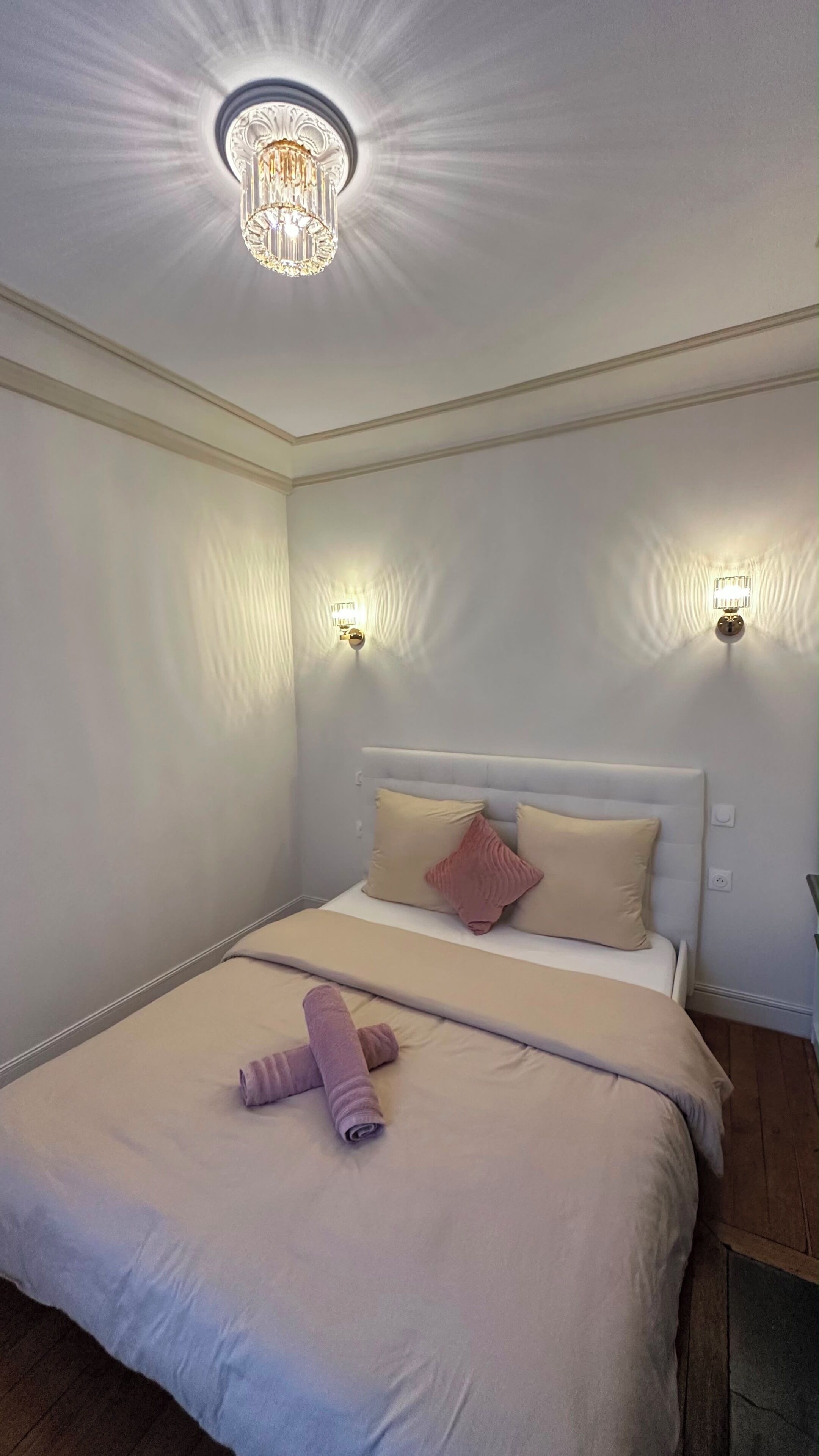 Een hotelkamer met een groot bed, twee wandlampen en een plafondlamp.