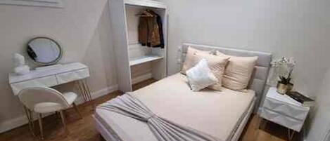 A bedroom with a bed, a bedside table, a chair, a wardrobe, and a mirror.