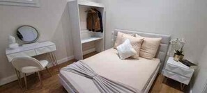 Ein Schlafzimmer mit einem Bett, einem Nachttisch, einem Stuhl, einem Kleiderschrank und einem Spiegel.