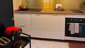 A modern kitchen with white cabinets, a black microwave, a Bosch coffee machine, and a red toaster. - Place du Trocadéro (5-minute walk) - Elegant 3-room apartment, 50 m² (max. 6 people) (Paris)