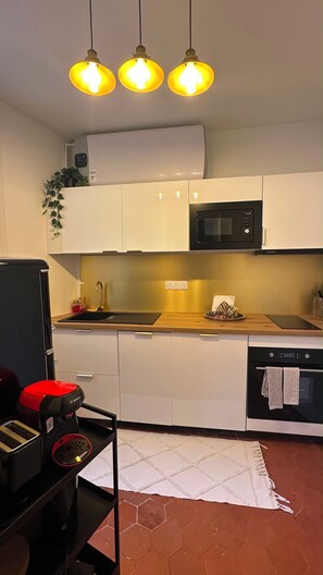 Eine moderne Küche mit weißen Schränken, einer schwarzen Mikrowelle, einer Bosch-Kaffeemaschine und einem roten Toaster.