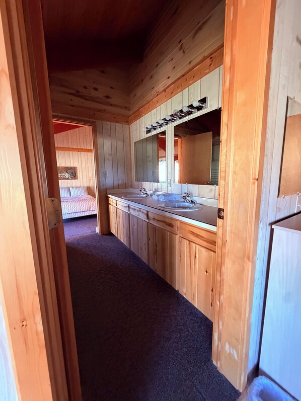 Interior de cabana de madeira com banheiro, incluindo pia, espelho e porta-toalhas.