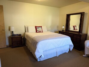 A hotel room with a bed, bedside tables, a dresser, a mirror, and a chair. - Rio Grande River and Ridge Lodge (South Fork)