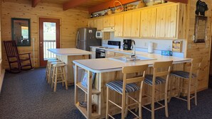 A cabin-style kitchen with wooden cabinets, a refrigerator, a microwave, and a coffee maker. - Rio Grande River and Ridge Lodge (South Fork)