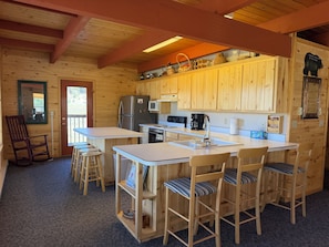 Eine Küchenzeile im Chalet-Stil mit Holzschränken, einem Kühlschrank, einer Mikrowelle und einer Kaffeemaschine.