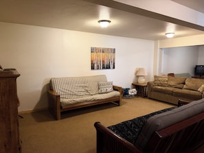 Uma sala de estar com dois sofás, uma luminária, um quadro e uma televisão.