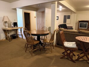 A room with a round wooden dining table, four chairs, a sofa, a television, and a lamp. - Rio Grande River and Ridge Lodge (South Fork)