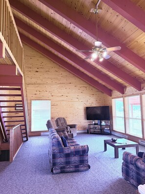 A spacious living room with a high ceiling, a large television, and a comfortable sofa. - Rio Grande River and Ridge Lodge (South Fork)