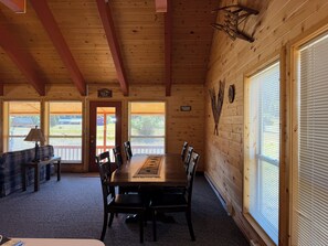 A wooden interior with a dining table, chairs, a lamp, and large windows. - Rio Grande River and Ridge Lodge (South Fork)