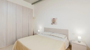 Une chambre à coucher avec un lit, des tables de chevet, une lampe sur pied et un tableau au mur.