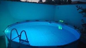 Une piscine ronde avec une échelle sur un côté, entourée d’un petit muret.