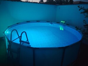 Una piscina circular con una escalera a un lado, rodeada por un muro bajo.