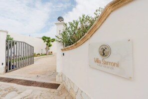 Una entrada con portón a Villa Sermoni, una propiedad vacacional, con un camino despejado que lleva al portón.
