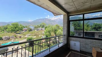 A room with a balcony overlooking a mountainous landscape.