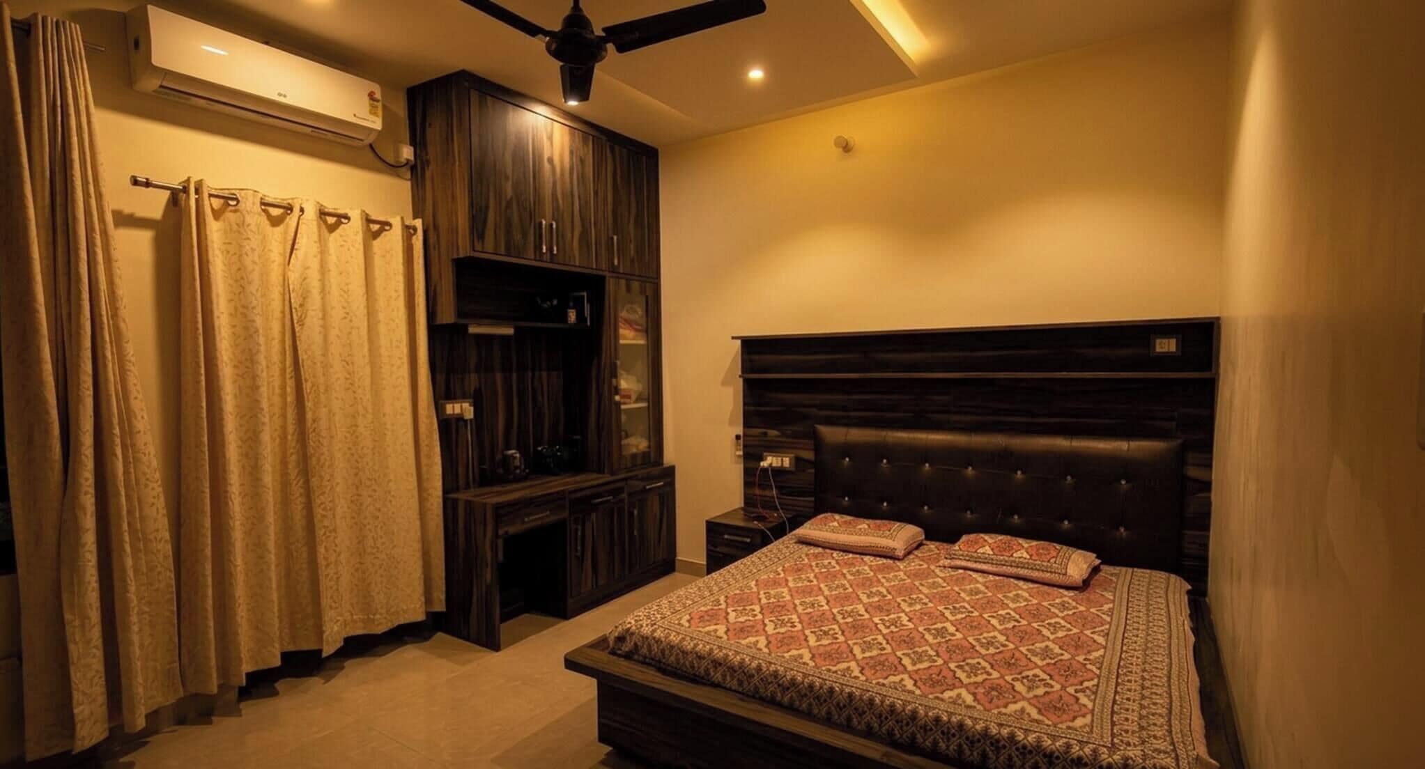 A bedroom with a bed, a wardrobe, a ceiling fan, and an air conditioning unit.