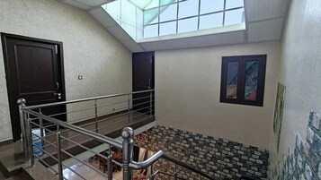 Un interior de varios niveles con una escalera, un tragaluz y una pared de piedra.