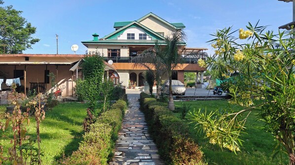 A two-story house with a stone pathway leading to the entrance.