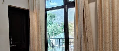 A room with a large window, a door, and an air conditioning unit.