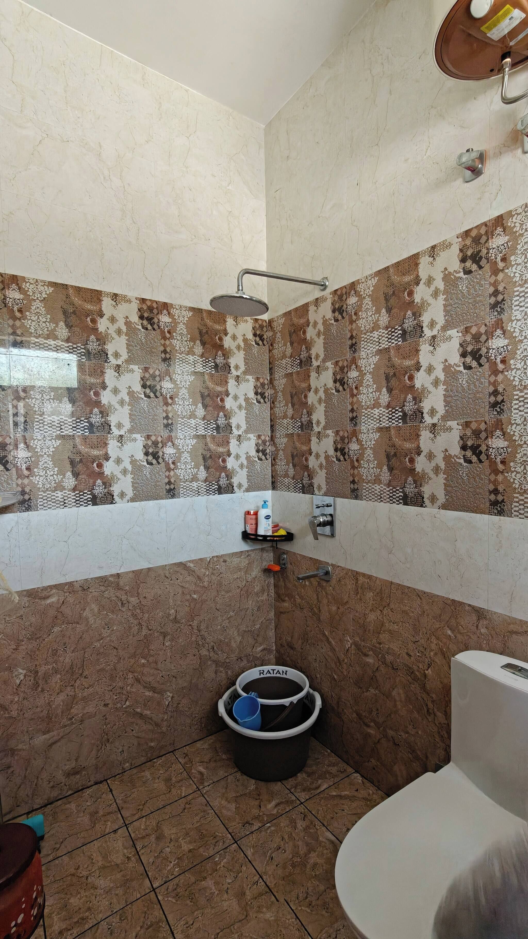 Un baño con ducha, inodoro y lavamanos con un cubo.