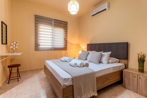 Ein Schlafzimmer mit Bett, Nachttisch, Lampe und einer Wand-Klimaanlage.