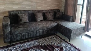 Ein Ecksofa mit einem gemusterten Teppich in einem Raum mit Backsteinwand.