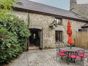 A stone building with a doorway, a small window, and a table with chairs outside. - Brimble Cottage at Dockwell Farm (Newton Abbot)