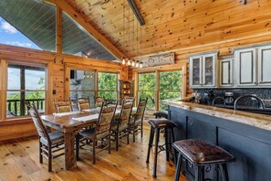 Ein Holzblockhaus-Innenraum mit Essbereich, Küche und großen Fenstern.