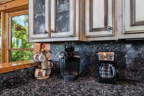 A kitchen with granite countertops, a Keurig coffee maker, and a coffee machine.