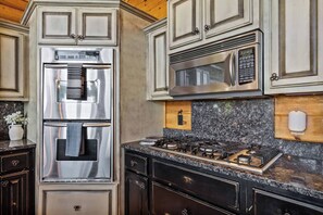 A kitchen with a stainless steel refrigerator, a microwave, and a gas stove.