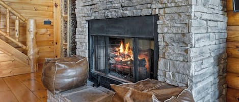 Una chimenea de piedra con fuego, paredes de madera y una escalera de madera.