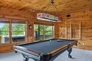 A pool table in a wooden cabin with a hanging license plate sign. - Luxury Log Cabin | Epic Views, Hot Tub, Sleeps 12 (Mineral Bluff)