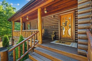 Eine Holzhütte mit Veranda, Fußmatte und einer Bärenstatue.
