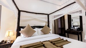 Een hotelkamer met een hemelbed, nachtkastje met lamp en spiegel aan de muur.