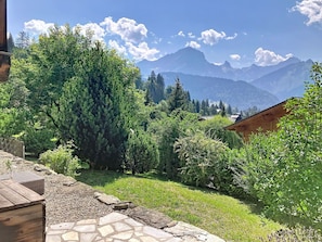 Ein Garten mit einem gepflasterten Weg, üppigem Grün und einer Bergsicht im Hintergrund.