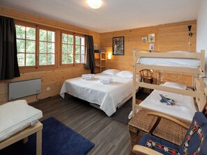 Ein Zimmer in einer Holzhütte mit einem Etagenbett, einem Schreibtisch, einem Stuhl und einem Fenster mit Vorhängen.