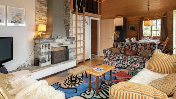 Una sala de estar acogedora con chimenea, televisor y comedor con mesa dispuesta para cuatro.