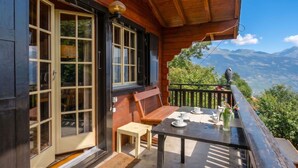 Una terraza de madera con una mesa dispuesta para el té, con vistas a un paisaje montañoso.