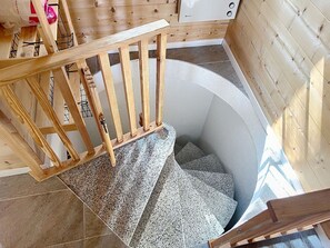Eine Holztreppe führt zu einem kleinen, runden Raum mit Fliesenboden.