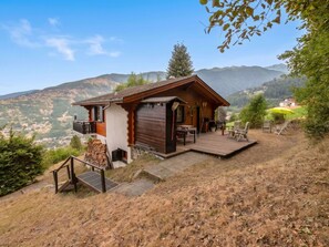 Eine Holzhütte mit Balkon, Terrasse und Blick auf die umliegenden Hügel.