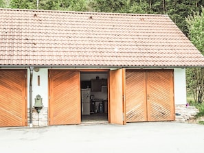 A building with a tiled roof, two wooden doors, and a visible kitchen area.