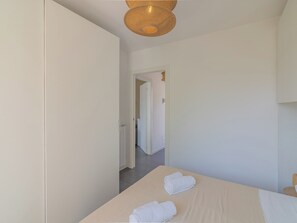 A hotel room with a bed, two towels, a woven ceiling light fixture, and a door leading to another room. - EnjoyIseoLake - Lake Serenity (Plassi)