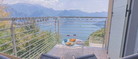 A balcony with a view of mountains, a table with food and drinks, and a hammock.
