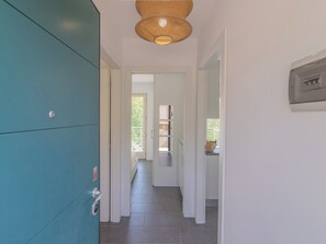 A hallway with a teal-colored cabinet, a door leading to a room, and a ceiling light fixture. - EnjoyIseoLake - Lake Serenity (Plassi)